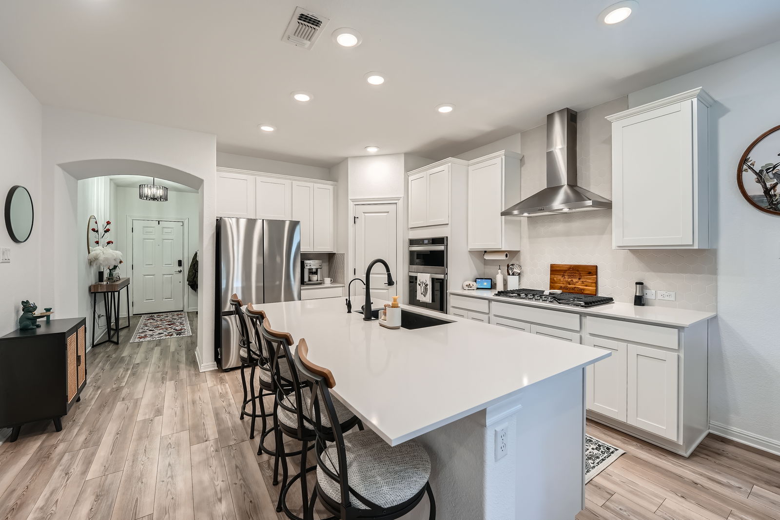 321 Georgia Lace Trail Georgetown, TX 78626 - Photo 8 of 27 Kitchen featuring a breakfast bar, appliances with stainless steel finishes, wall chimney exhaust hood, a center island with sink, and white cabinetry