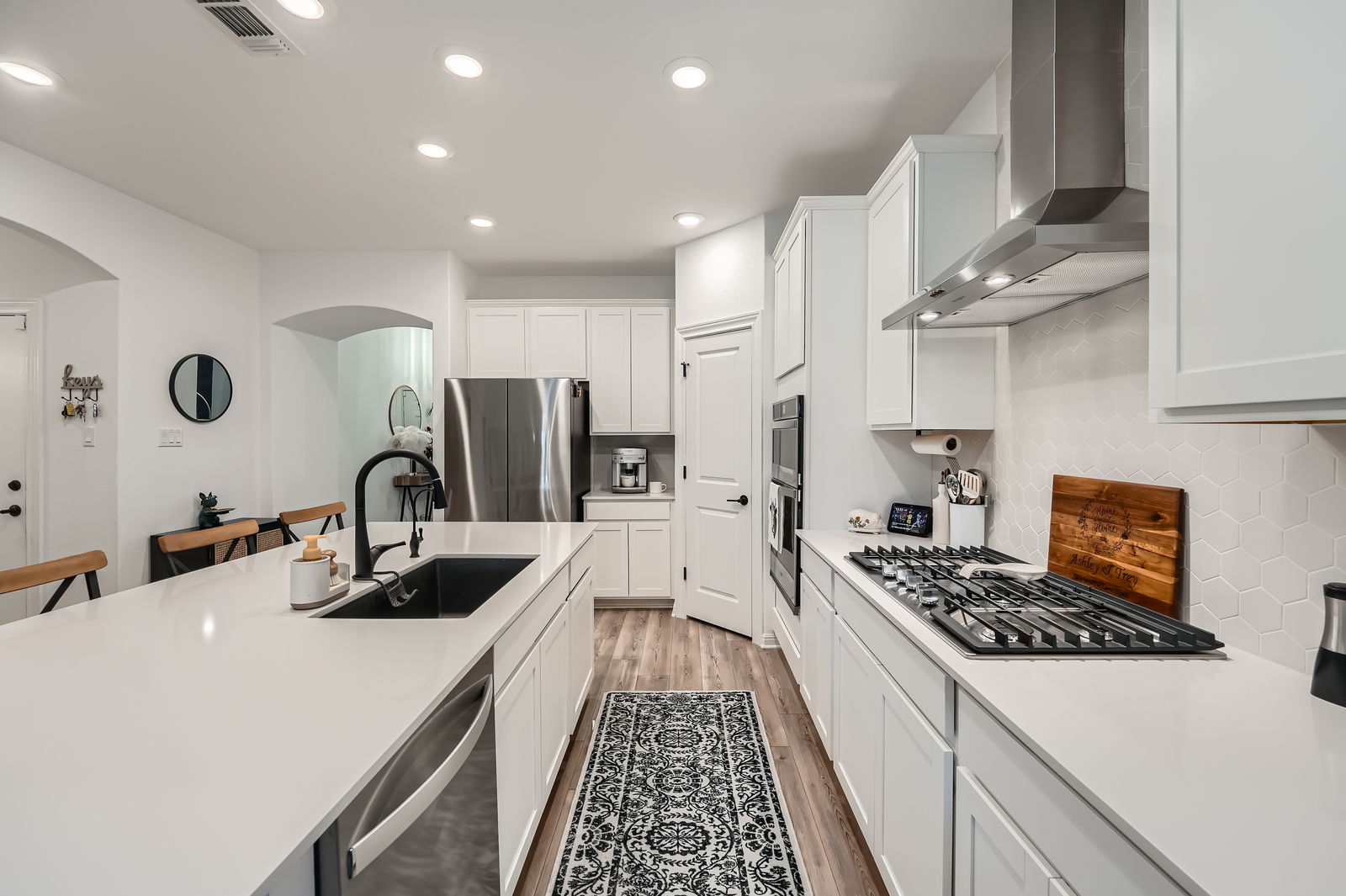 321 Georgia Lace Trail Georgetown, TX 78626 - Photo 9 of 27 Kitchen with white cabinetry, light wood finished floors, wall chimney exhaust hood, appliances with stainless steel finishes, and decorative backsplash