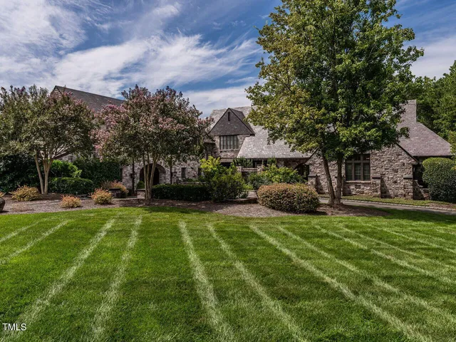 a view of a house with a big yard and large trees