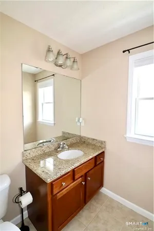 a bathroom with a granite countertop sink toilet and mirror