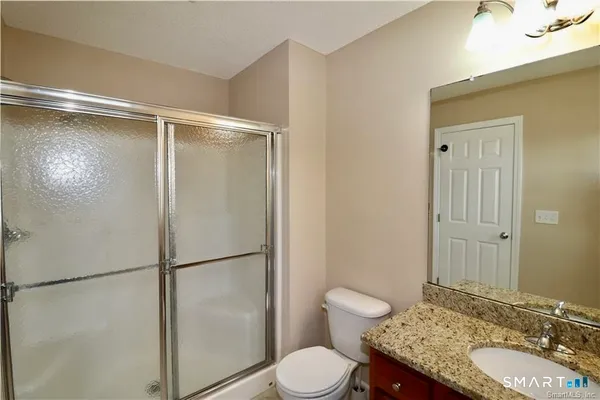 a bathroom with a granite countertop sink toilet and shower