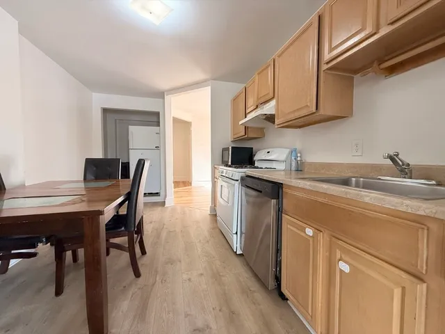 a kitchen with stainless steel appliances a table chairs in it and wooden floors