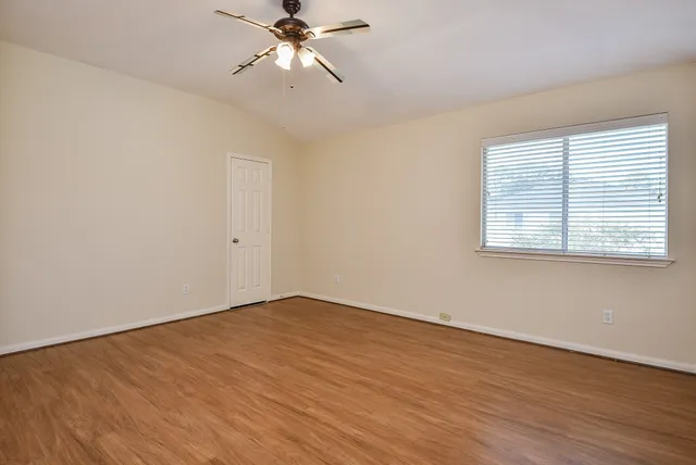 a view of an empty room with wooden floor and a window