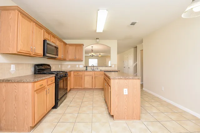 a kitchen with stainless steel appliances granite countertop a stove a sink and a microwave