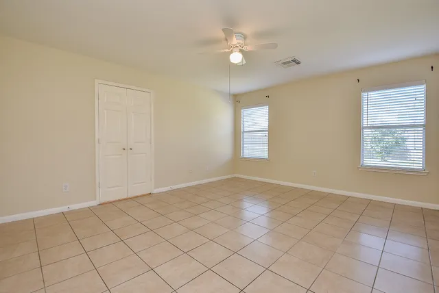 an empty room with windows and fan