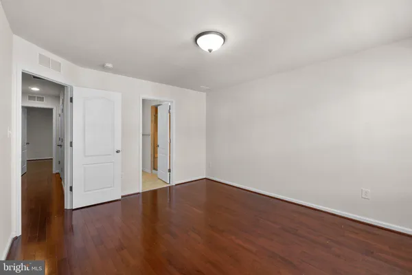 a view of an empty room with wooden floor and a mirror