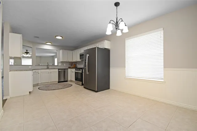 a kitchen with stainless steel appliances granite countertop a refrigerator a sink dishwasher a stove and white cabinets with wooden floor