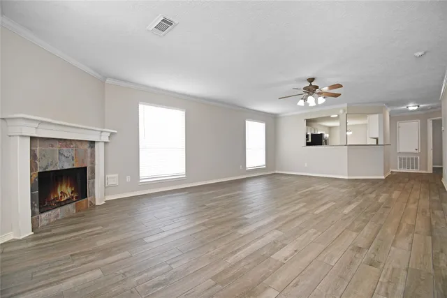 a view of an empty room with wooden floor and a fireplace