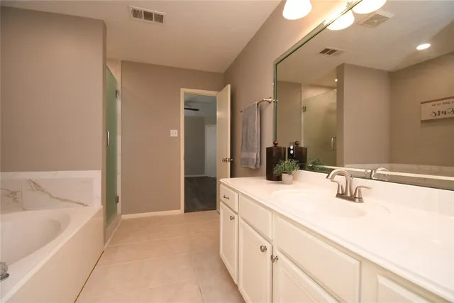 a bathroom with a double vanity sink mirror and bathtub