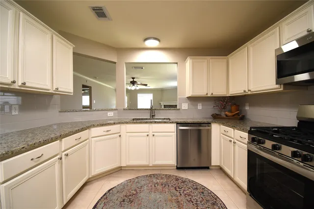 a kitchen with granite countertop white cabinets and appliances