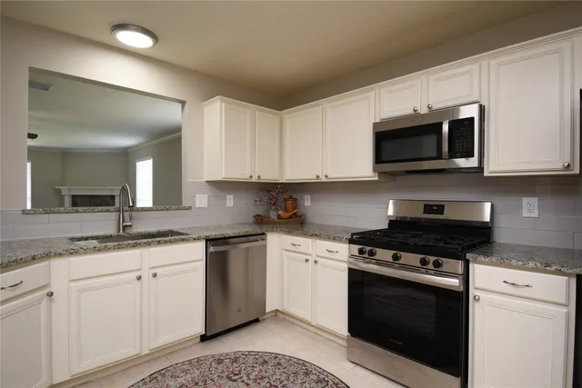 a kitchen with granite countertop white cabinets white stainless steel appliances and a sink