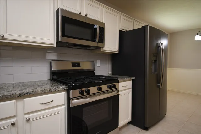a kitchen with stainless steel appliances granite countertop white cabinets and black stove top oven with granite countertops