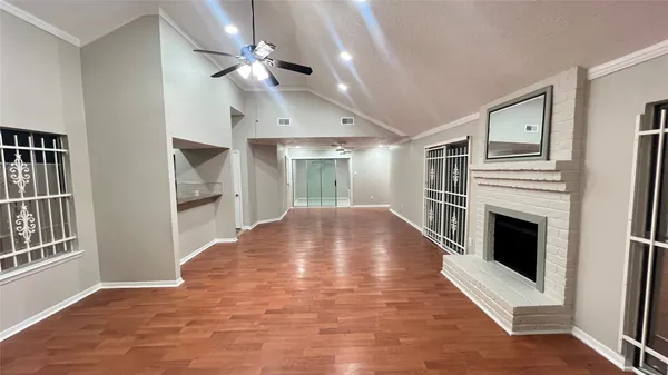 a view of an empty room with kitchen and fireplace