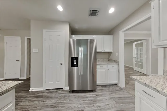 an empty room with wooden floor cabinet and windows