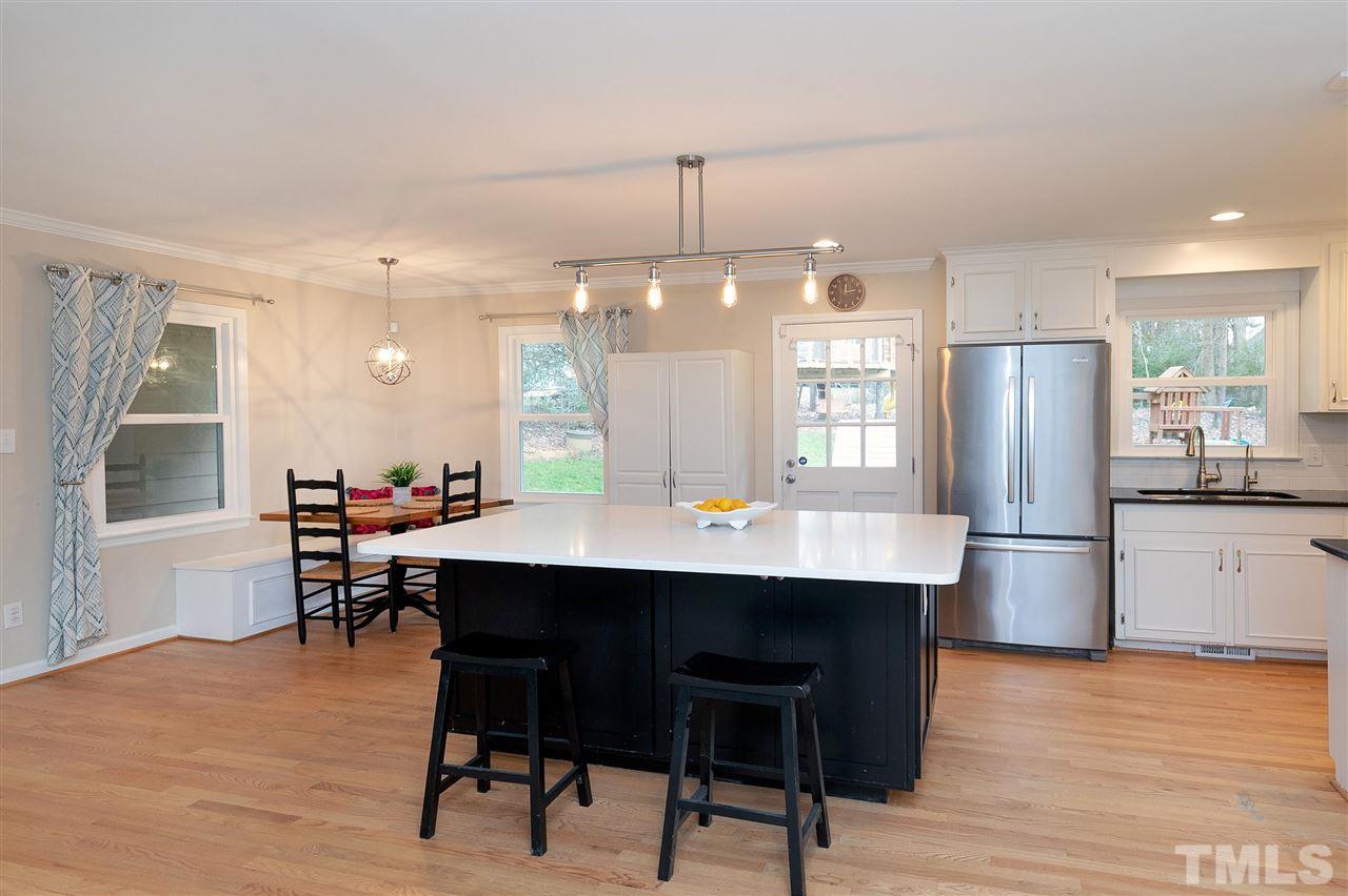 6509 Wrenwood Avenue Raleigh, NC 27607 - Photo 4 of 29 a kitchen with a dining table chairs refrigerator and cabinets