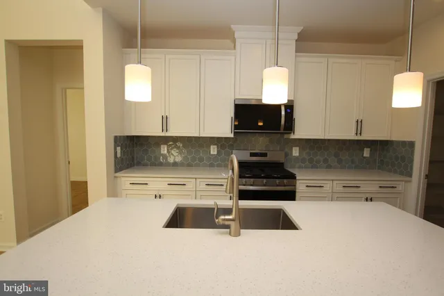 a kitchen with stainless steel appliances a stove a sink a microwave a refrigerator and cabinets