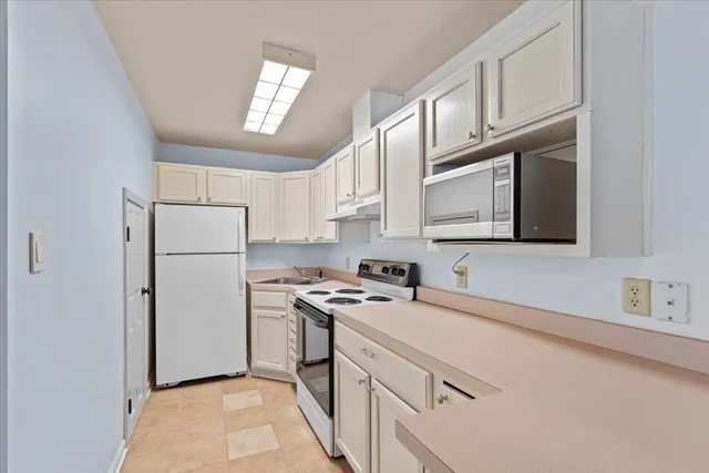 a kitchen with stainless steel appliances granite countertop a refrigerator a stove a sink and a microwave