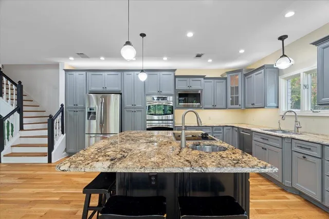 a kitchen with kitchen island granite countertop a sink and refrigerator