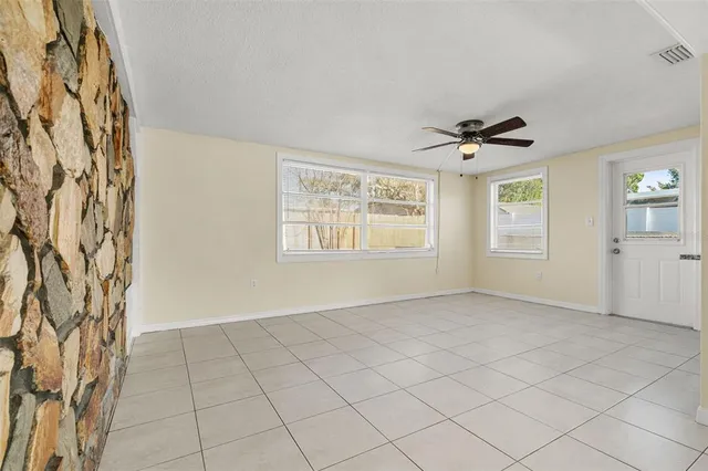 an empty room with windows and fan