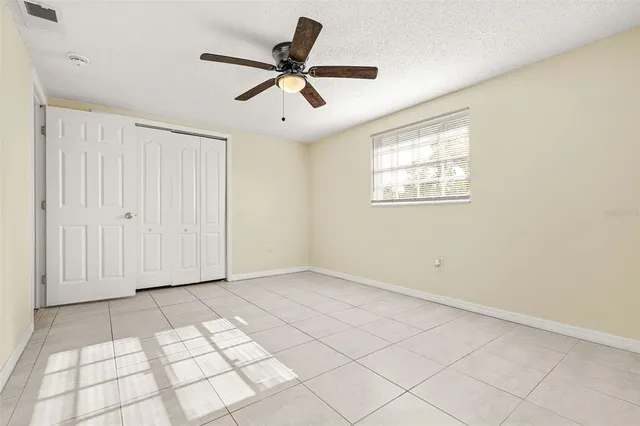 a view of an empty room and chandelier fan