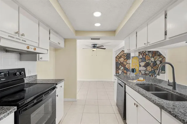 a kitchen with granite countertop a sink stove and cabinets