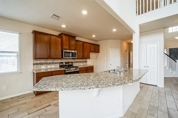 a kitchen with granite countertop kitchen island stainless steel appliances a sink stove and cabinets
