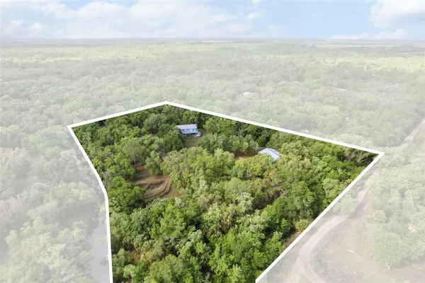 an aerial view of residential house with outdoor space and trees all around