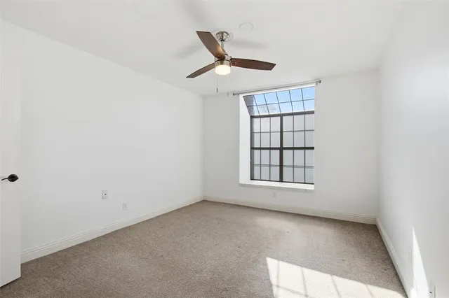 an empty room with ceiling fan and window