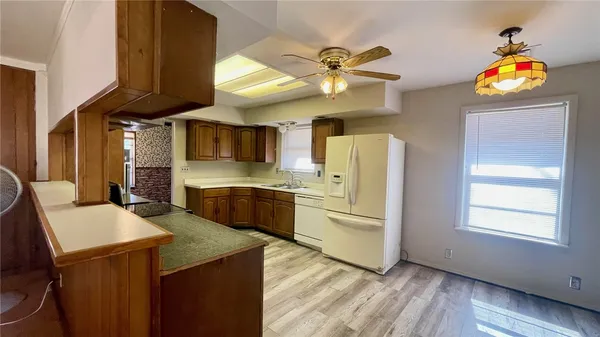 a kitchen with stainless steel appliances kitchen island granite countertop a refrigerator a sink dishwasher a stove and a dining table with wooden floor