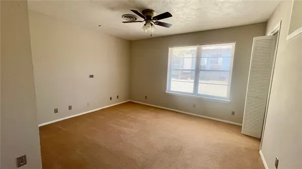 an empty room with a window and a fan