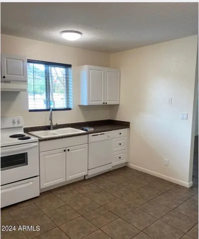 a kitchen with granite countertop white cabinets white appliances with a sink and dishwasher