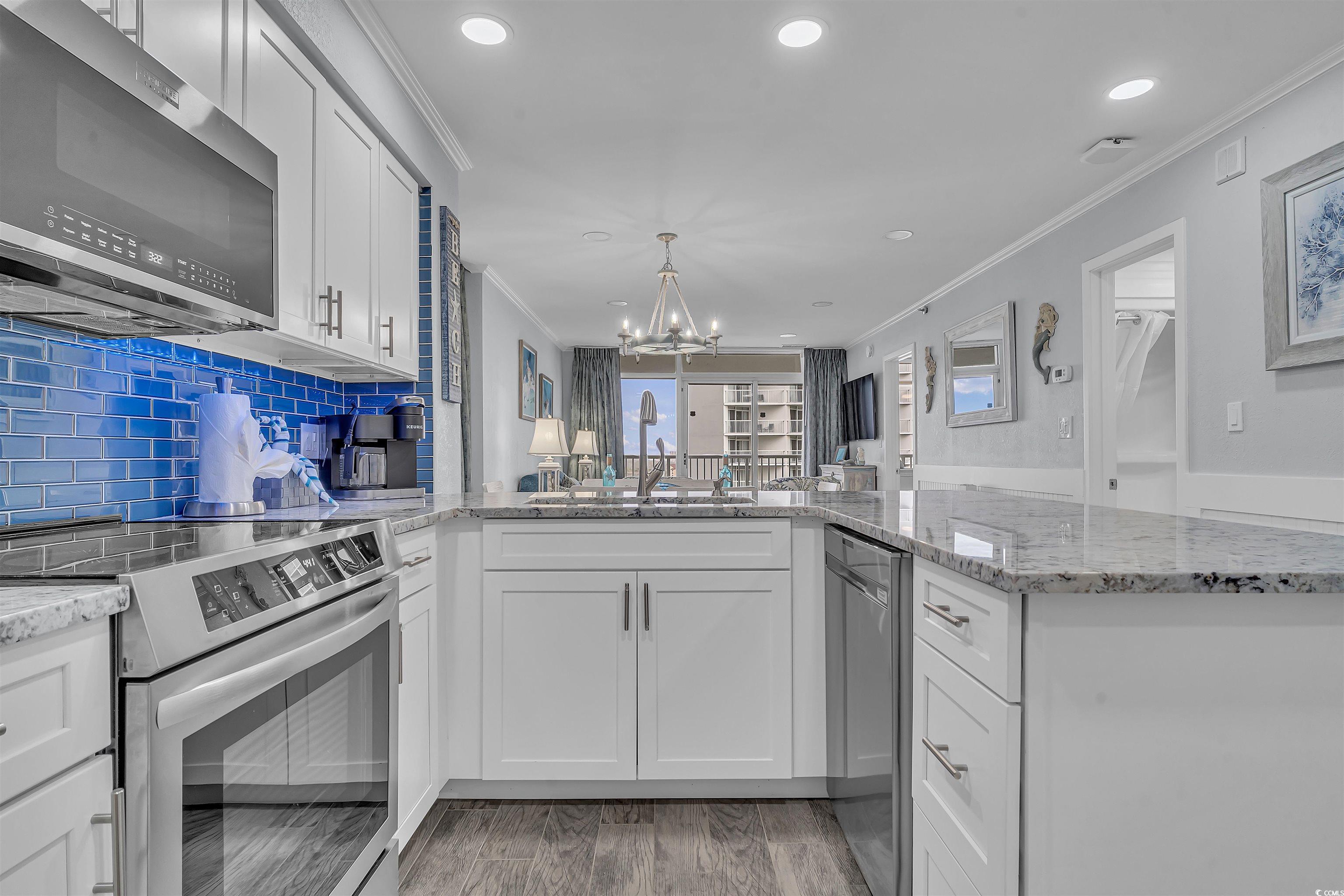 161 Seawatch Drive, Unit 1118 Myrtle Beach, SC 29572 - Photo 4 of 40 Kitchen with appliances with stainless steel finishes, light stone countertops, white cabinets, ornamental molding, and a chandelier