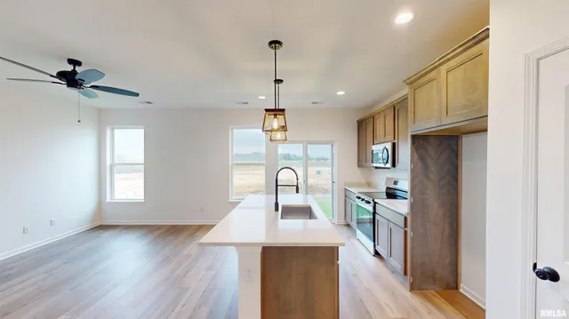 a view of a kitchen center island with wooden floor stainless steel appliances cabinets and a sink