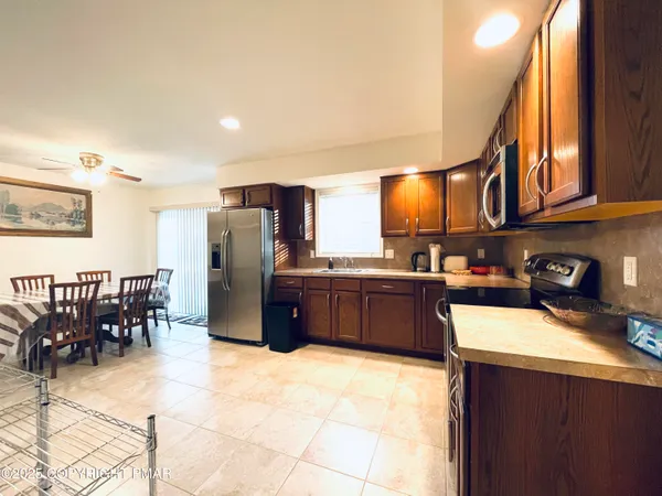 a kitchen with stainless steel appliances granite countertop a refrigerator a sink a stove a dining table and chairs