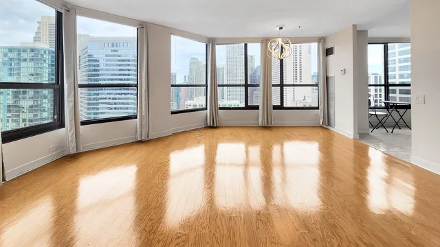 a view of empty room with floor to ceiling window and wooden floor