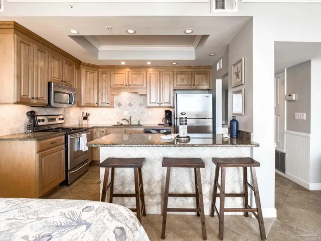 a kitchen with stainless steel appliances granite countertop a sink a stove a refrigerator with a dining table and chairs