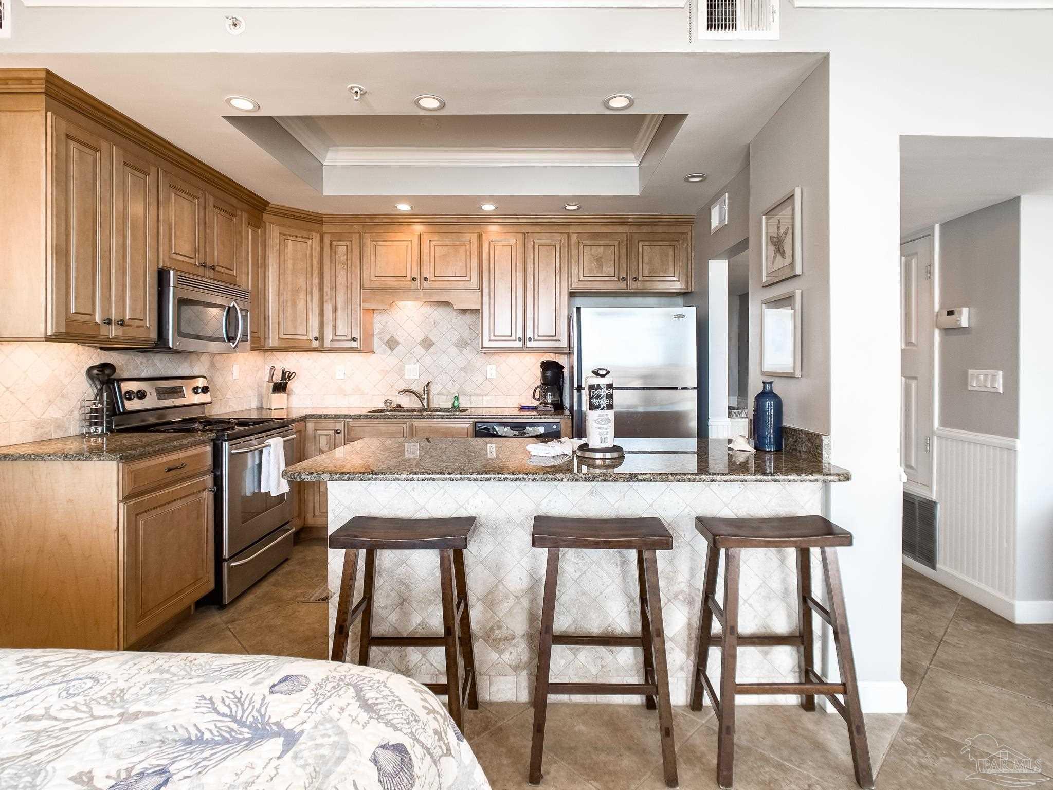 16287 Perdido Key Drive, Unit 104 Pensacola, FL 32507 - Photo 11 of 32 a kitchen with stainless steel appliances granite countertop a sink a stove a refrigerator with a dining table and chairs