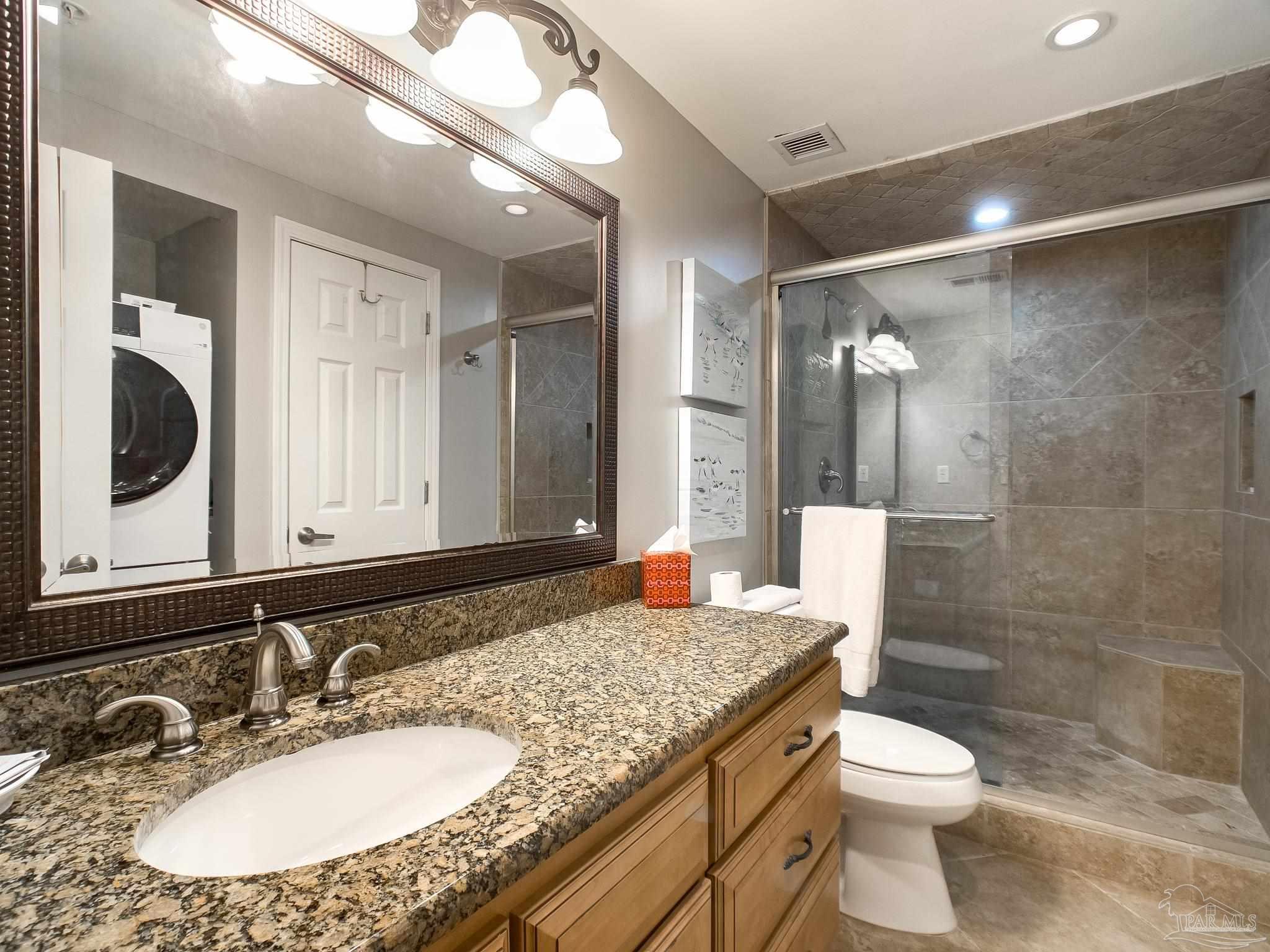 16287 Perdido Key Drive, Unit 104 Pensacola, FL 32507 - Photo 15 of 32 a bathroom with a granite countertop sink a toilet a mirror and shower