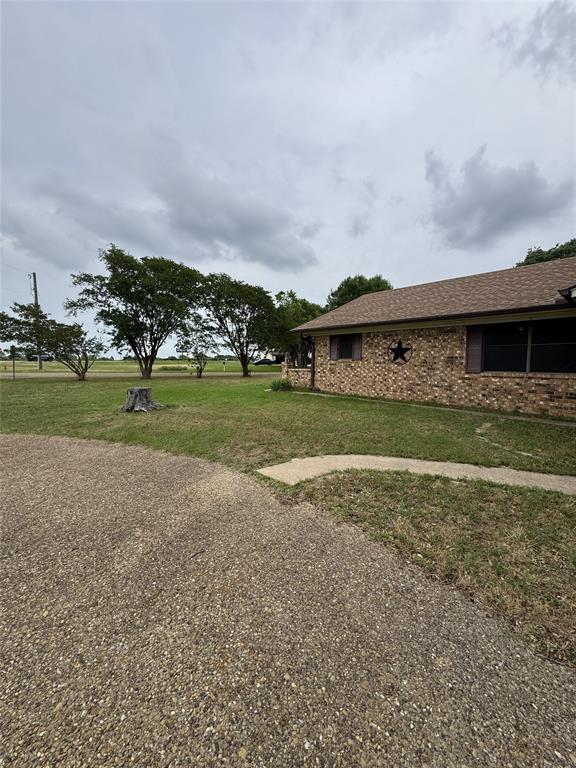 636 East Kempner Street Mabank, TX 75147 - Photo 3 of 28 Brick exterior featuring a brown shingle roof, dark window shutters, and a decorative star accent