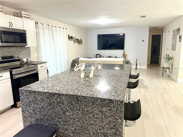 a kitchen with stainless steel appliances kitchen island granite countertop a stove a sink a microwave and refrigerator