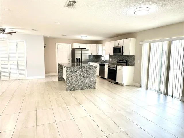 a living room with stainless steel appliances kitchen island granite countertop a large window and a couch