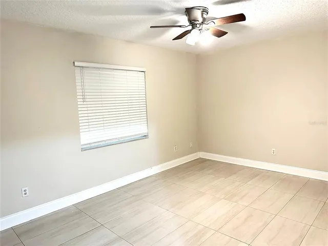 an empty room with windows and fan