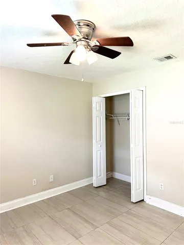 an empty room with closet and a chandelier fan