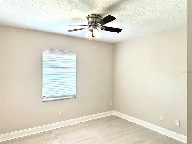 an empty room with a window and a fan