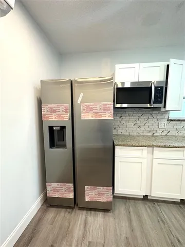 a kitchen with granite countertop white cabinets and stainless steel appliances