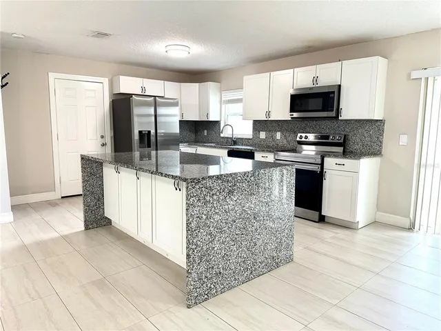 a kitchen with stainless steel appliances granite countertop a refrigerator and a stove top oven