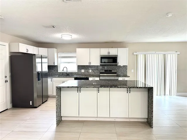 a kitchen with stainless steel appliances granite countertop a refrigerator and a stove top oven