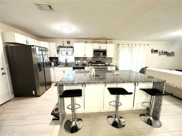 a kitchen with stainless steel appliances kitchen island granite countertop a refrigerator and a stove top oven