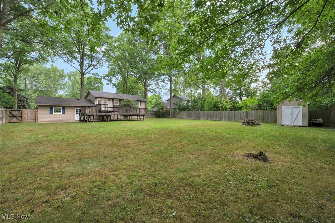 47655 Cooper Foster Park Road Amherst, OH 44001 - Photo 43 of 49 Fenced backyard featuring a shed, a wooden deck, and view of scattered trees