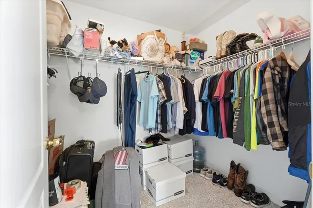 a view of walk in closet with clothes and shoes